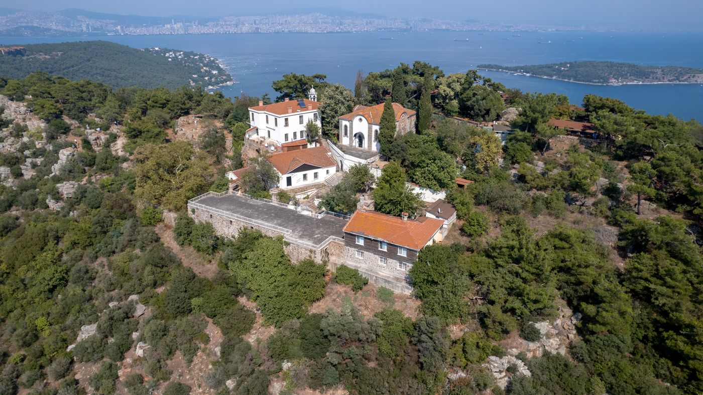 Aerial view of the Aya Yorgi (St George) monastery complex on a wooded Büyükada hilltop, with the Sea of Marmara and other islands behind